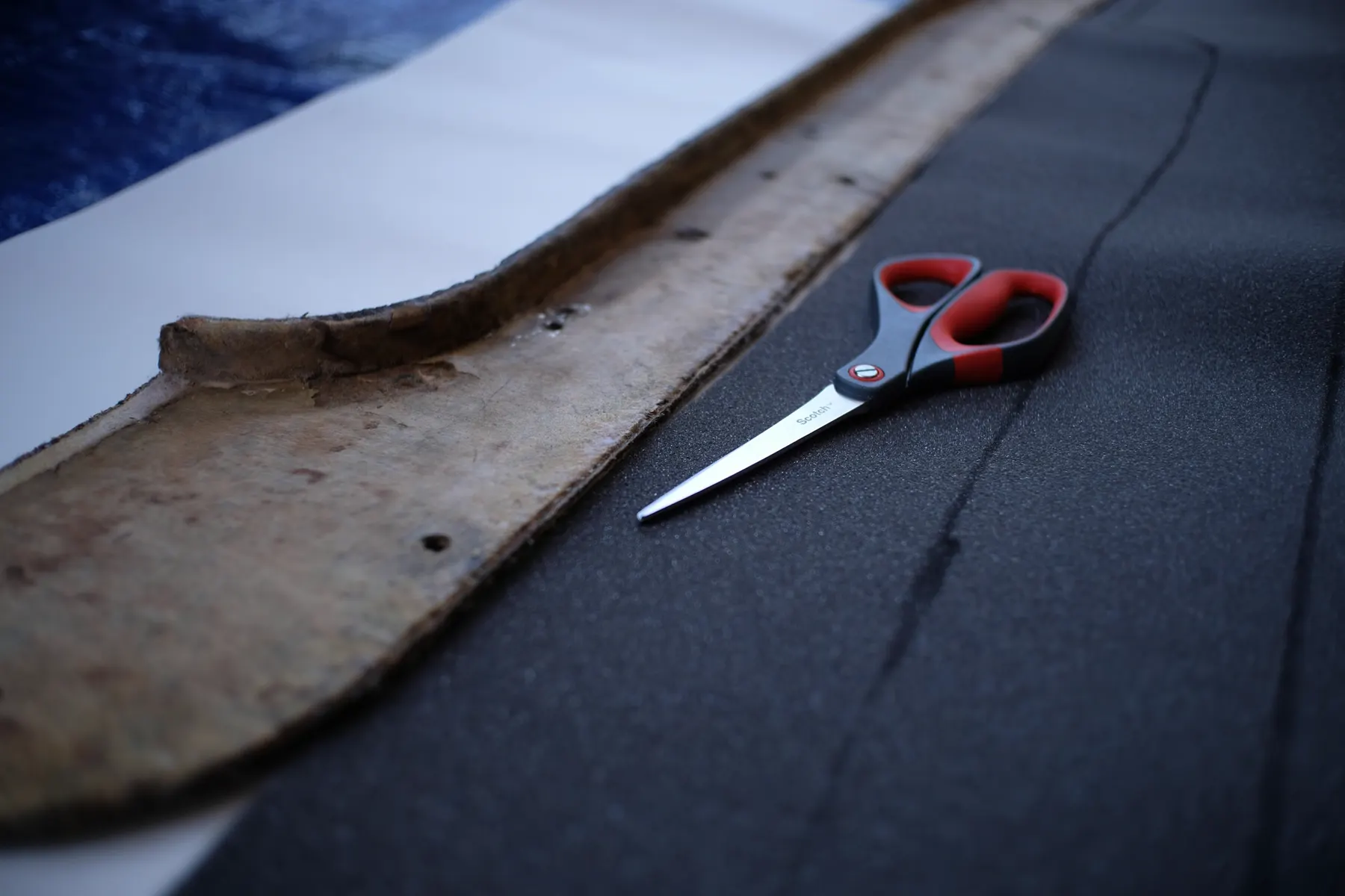 Scissors resting on dark cloth beside a worn pattern piece